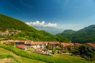 A hillside village below a snow-capped ridge, Italy