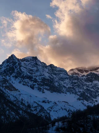 A snow-covered peak under sunset-lit clouds, Italy